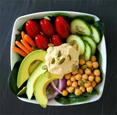 spinach salad with avocado, chickpea, tomato, cucumber, carrots