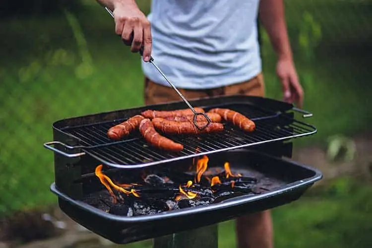 man barbecuing hot dogs