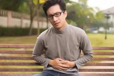 man on bench with stomach ache