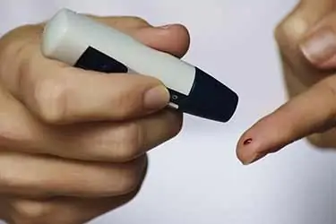 diabetic man pricking finger for blood glucose test